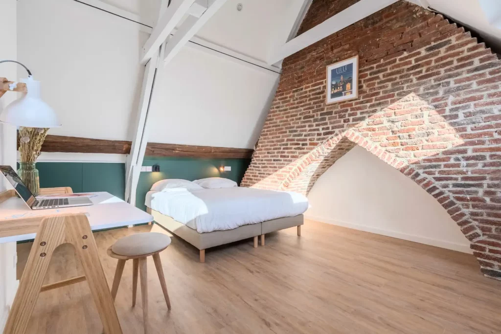 Chambre sous combles avec mur en briques voûté et poutres blanches — Maison 3 Mollettes, coliving IvyNest dans le Vieux-Lille