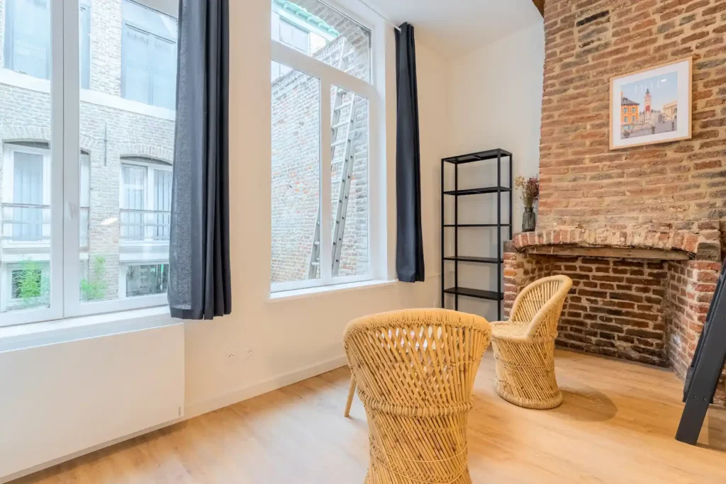 Coin salon avec fauteuils en rotin, cheminée en briques — Maison 3 Mollettes, coliving IvyNest dans le Vieux-Lille