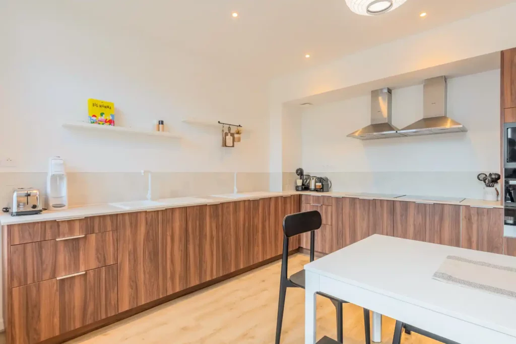 Cuisine en bois avec double évier, hottes inox et table blanche — Maison Centre, coliving IvyNest à La Madeleine