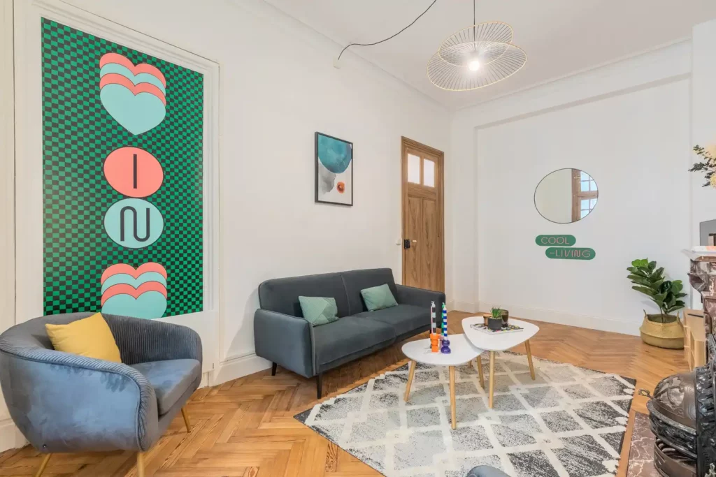 Salon avec grande affiche verte, canapé bleu-gris, fauteuil et parquet — Maison Lavoisier, coliving IvyNest à Lille Centre