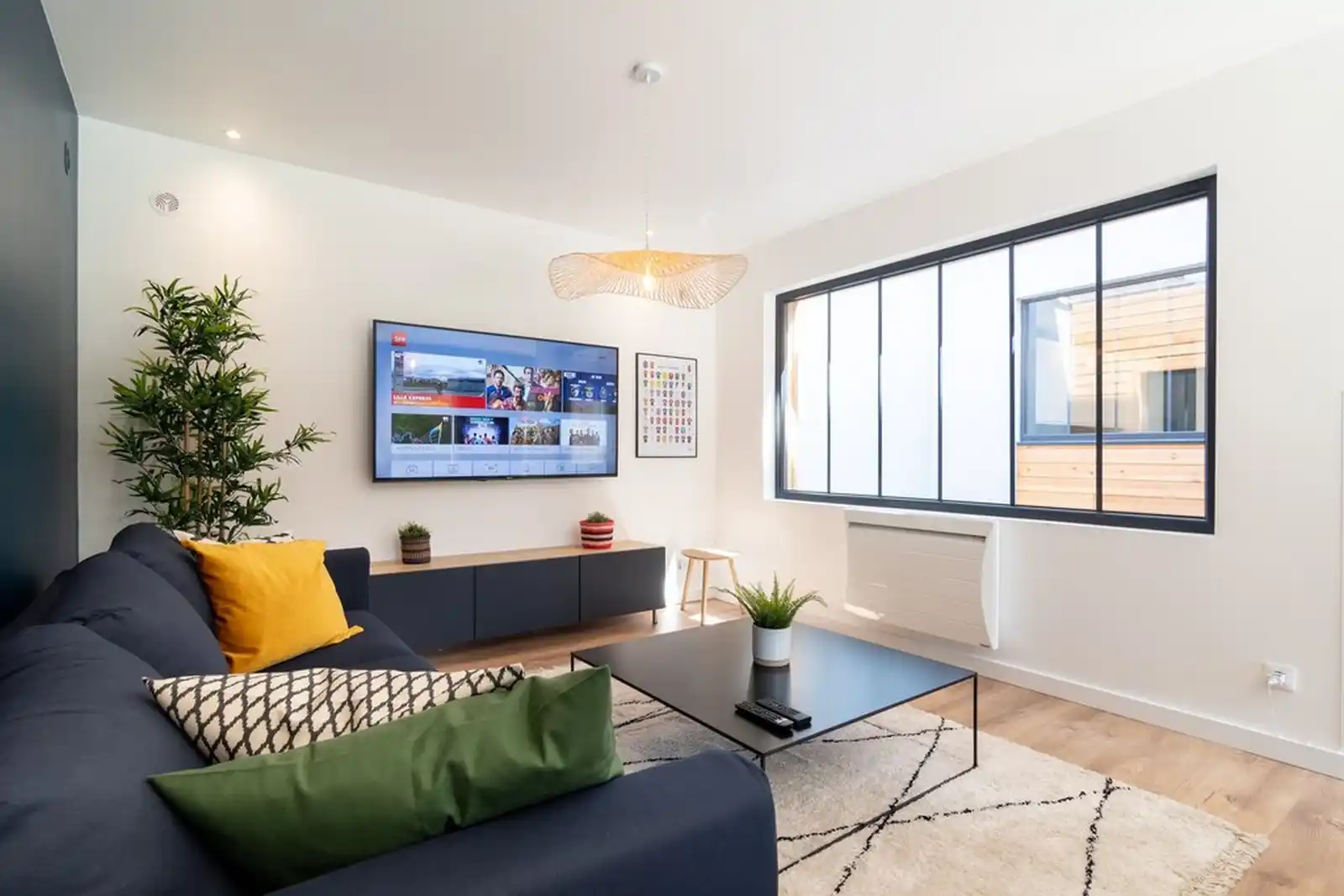 Salon avec télévision, canapé bleu marine et tapis berbère — Maison Bourg, coliving IvyNest à Lomme