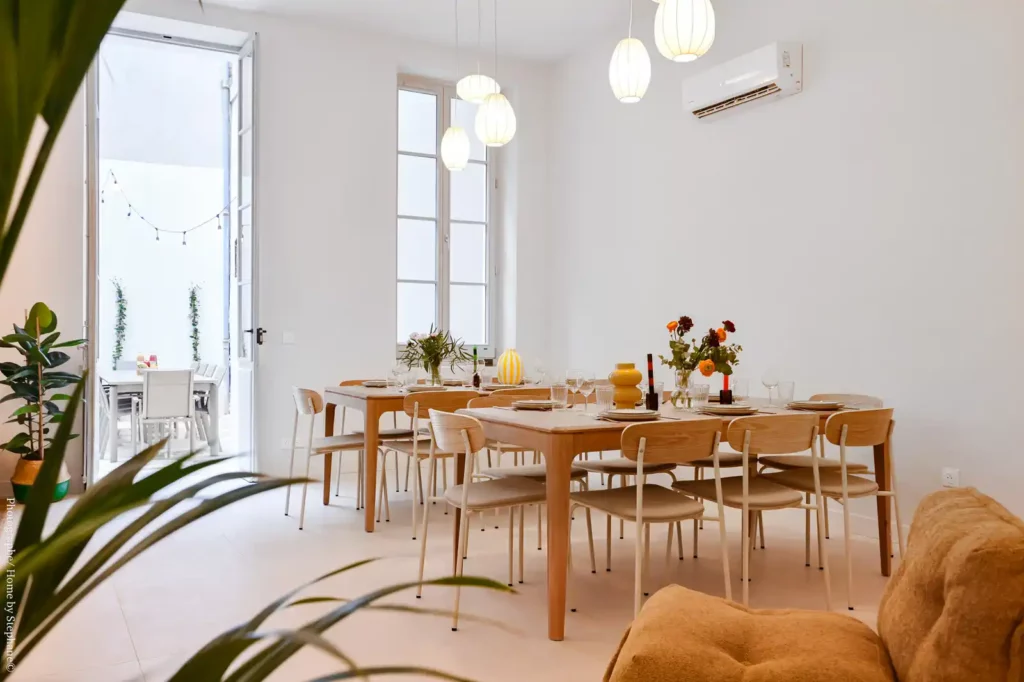 Salle à manger avec grande table en bois, chaises et porte-fenêtre — Maison Les Réformés, coliving IvyNest à Marseille