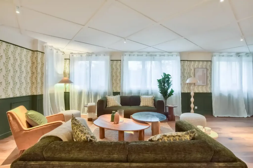 Salon avec canapé vert côtelé, fauteuil rose et rideaux blancs — Maison Fontenay-aux-Roses, coliving IvyNest (Île-de-France)