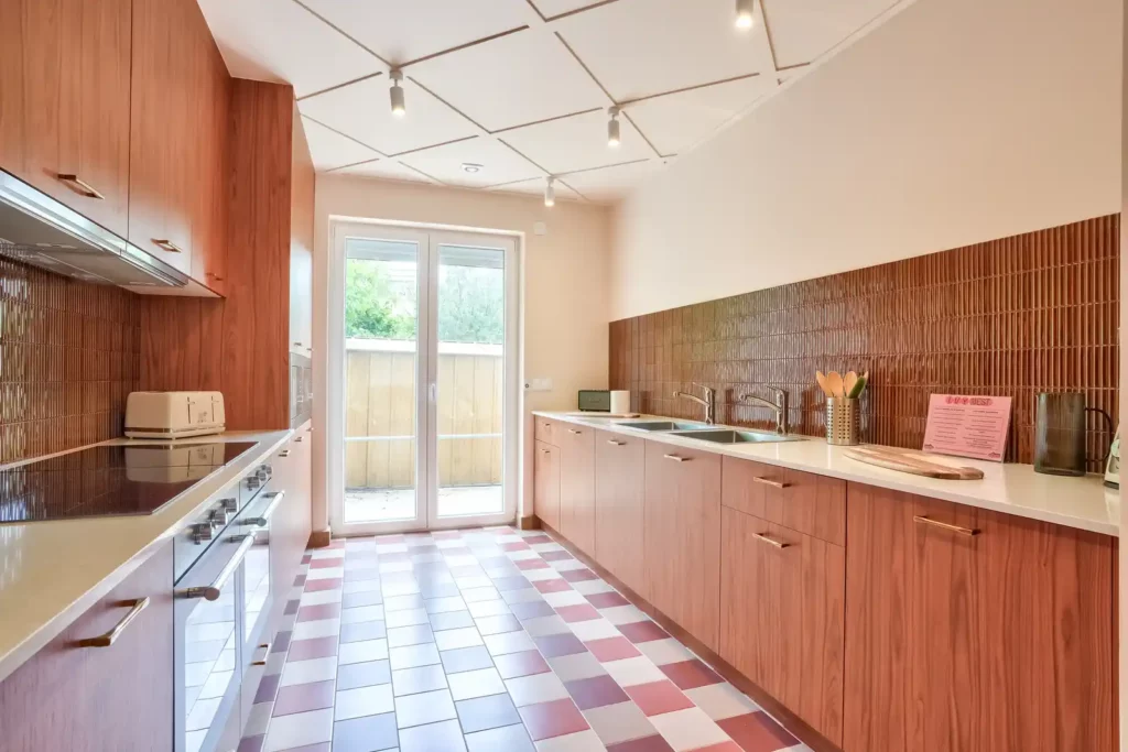 Cuisine équipée avec porte-fenêtre sur terrasse et sol damier — Maison Issy-les-Moulineaux, coliving IvyNest (Île-de-France)