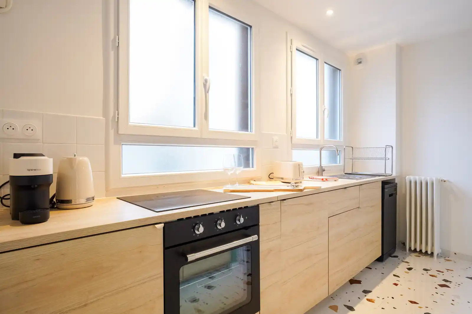 Cuisine équipée en bois clair avec four, plaques et sol terrazzo — Maison Kremlin-Bicêtre, coliving IvyNest (Île-de-France)