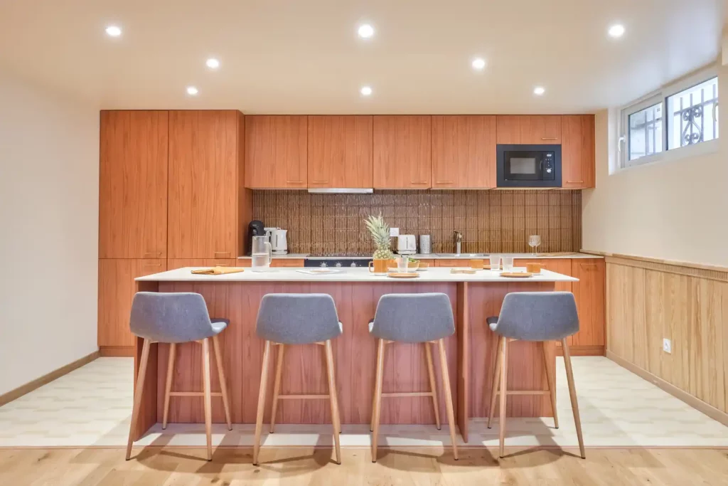Cuisine vue de face avec îlot, quatre tabourets et crédence brune — Maison Villejuif Hamon, coliving IvyNest à Villejuif