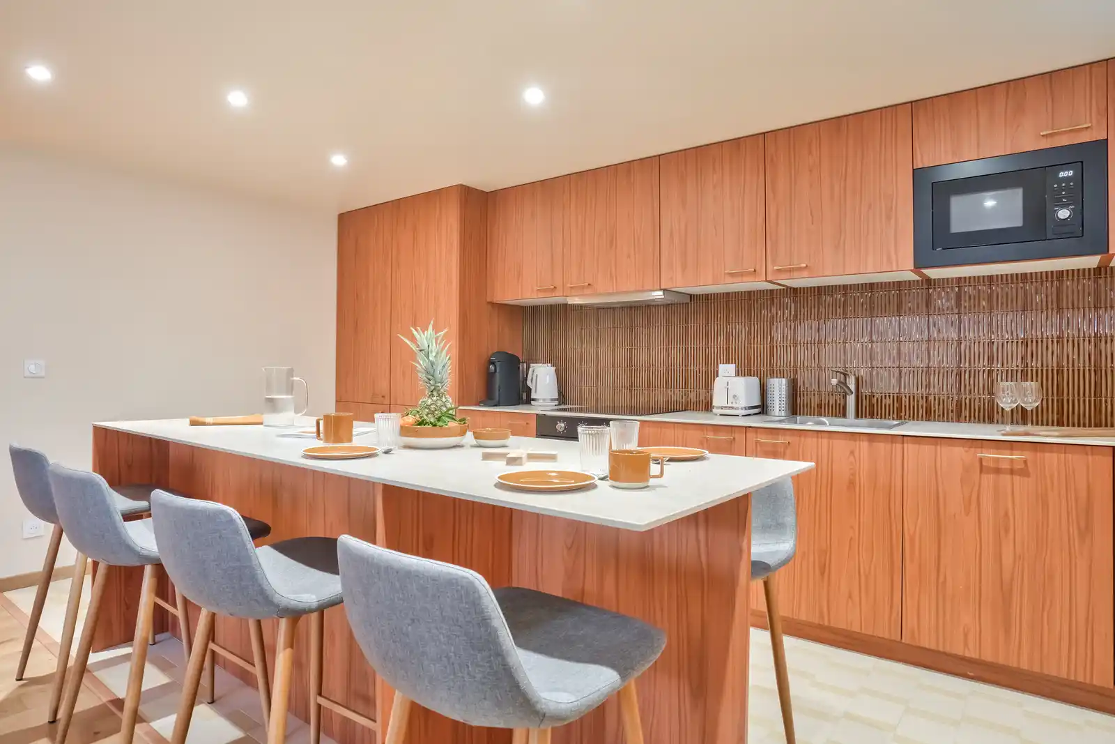 Îlot de cuisine blanc avec tabourets gris et four à micro-ondes — Maison Villejuif Hamon, coliving IvyNest à Villejuif