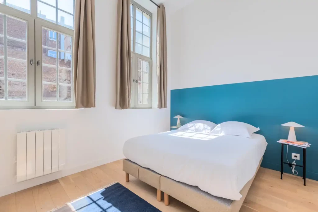 Chambre avec mur bleu canard, lit double et grandes fenêtres — Maison Saint-Étienne, coliving IvyNest à Lille Centre