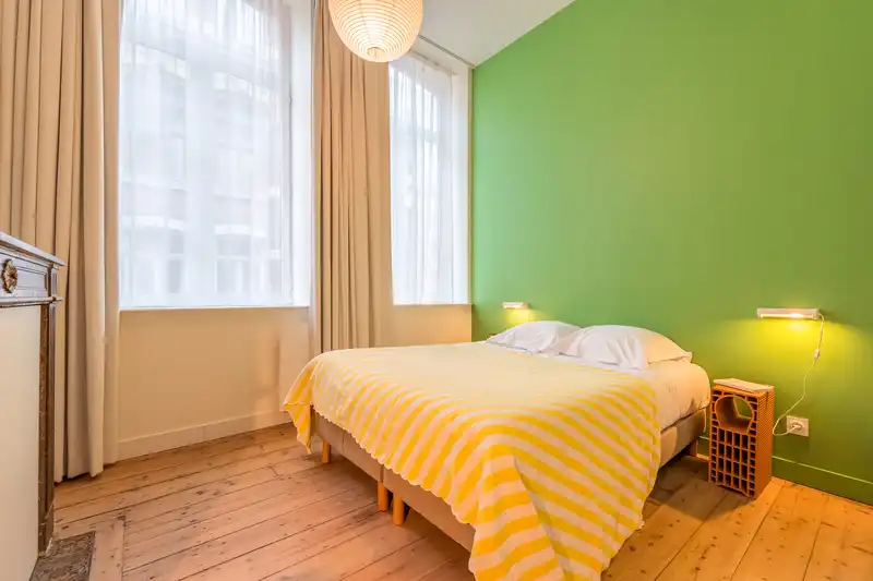 Chambre au mur vert avec lit double à plaid jaune rayé — Maison Rousseau, coliving IvyNest dans le Vieux-Lille