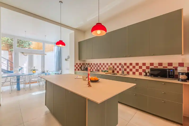 Cuisine ouverte avec îlot central, placards verts et lampes rouges — Maison 40 Solférino, coliving IvyNest à Lille Vauban