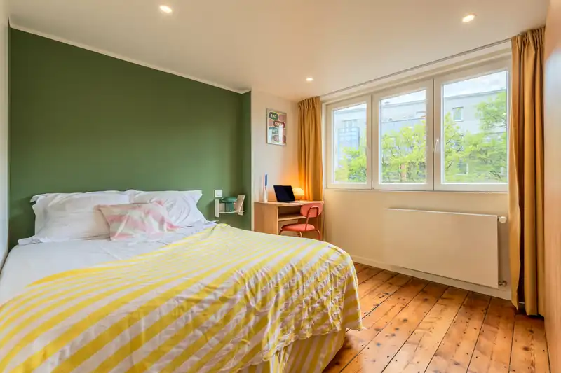Chambre avec mur vert, lit à rayures jaunes et parquet ancien — Maison 40 Solférino, coliving IvyNest à Lille Vauban