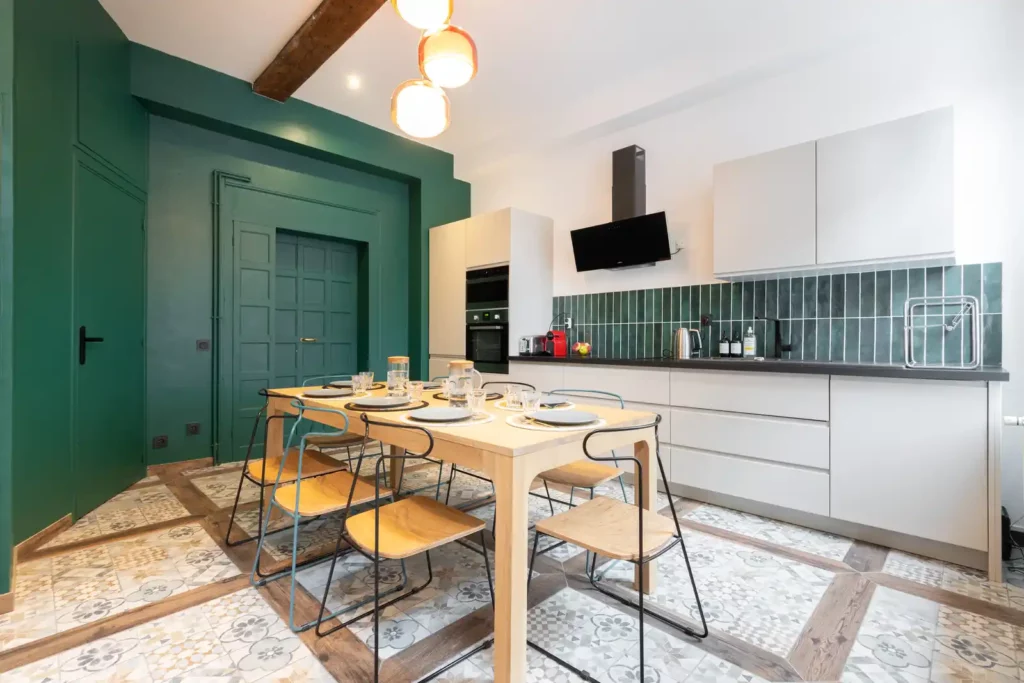 Salle à manger en bois et cuisine blanche à crédence verte — Maison Archives, coliving IvyNest dans le Vieux-Lille