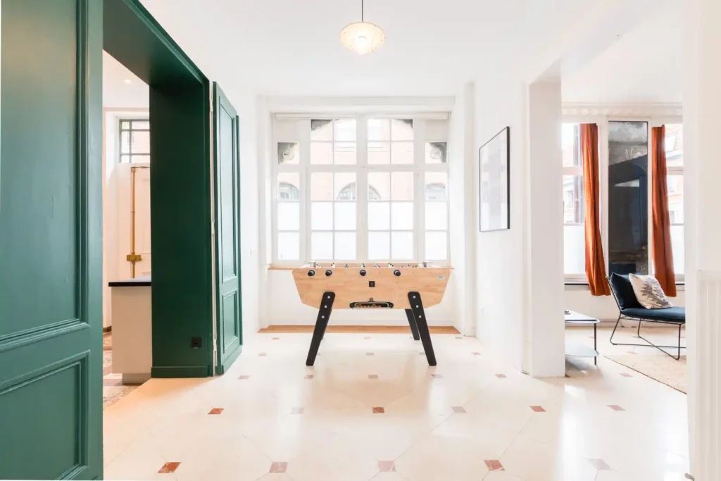 Salle de jeux lumineuse avec baby-foot et carrelage losanges — Maison Archives, coliving IvyNest dans le Vieux-Lille