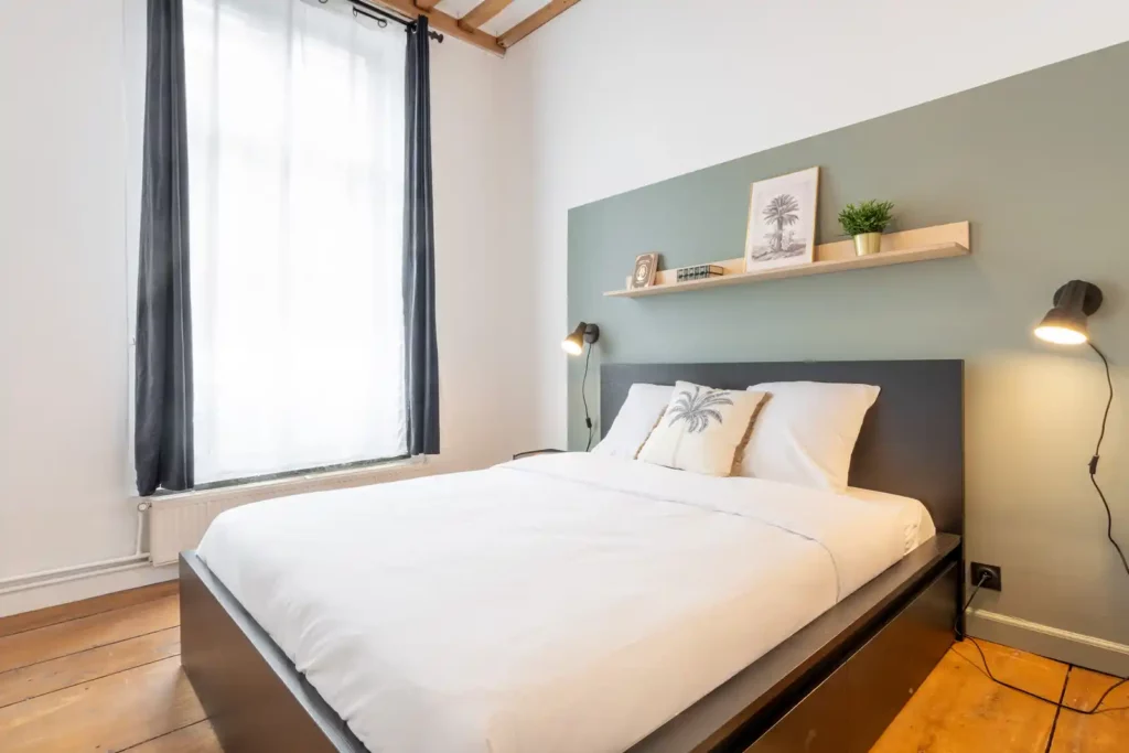 Chambre avec lit double, tête de lit vert sauge et parquet ancien — Maison Archives, coliving IvyNest dans le Vieux-Lille