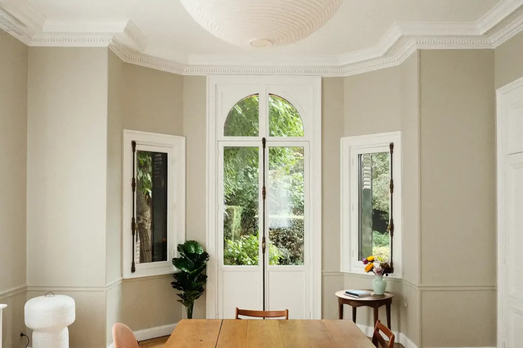 Salle à manger à moulures avec grande table en bois et porte-fenêtre — Maison Bonte-Pollet, coliving IvyNest à Lille Vauban