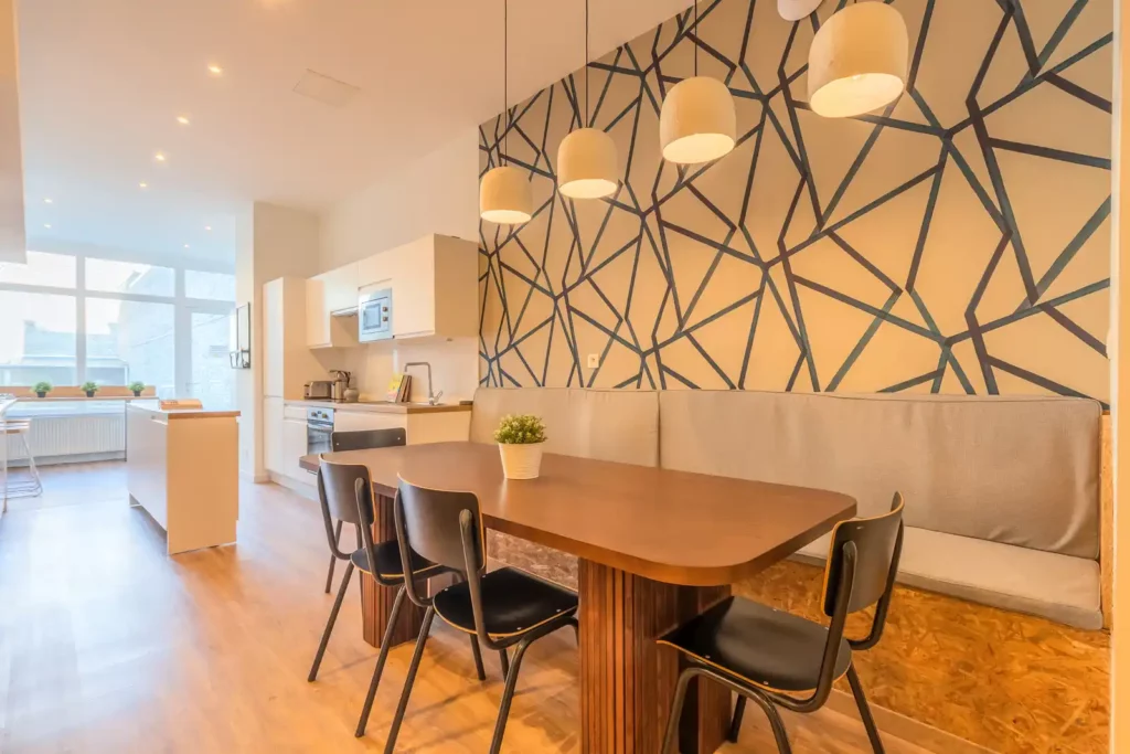 Coin repas avec table en bois, banquette grise et papier peint graphique — Maison Liberté, coliving IvyNest à Lille Centre