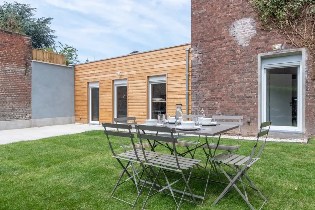 Jardin avec pelouse, table de repas pliante et façade en bois — Maison Bourg, coliving IvyNest à Lomme