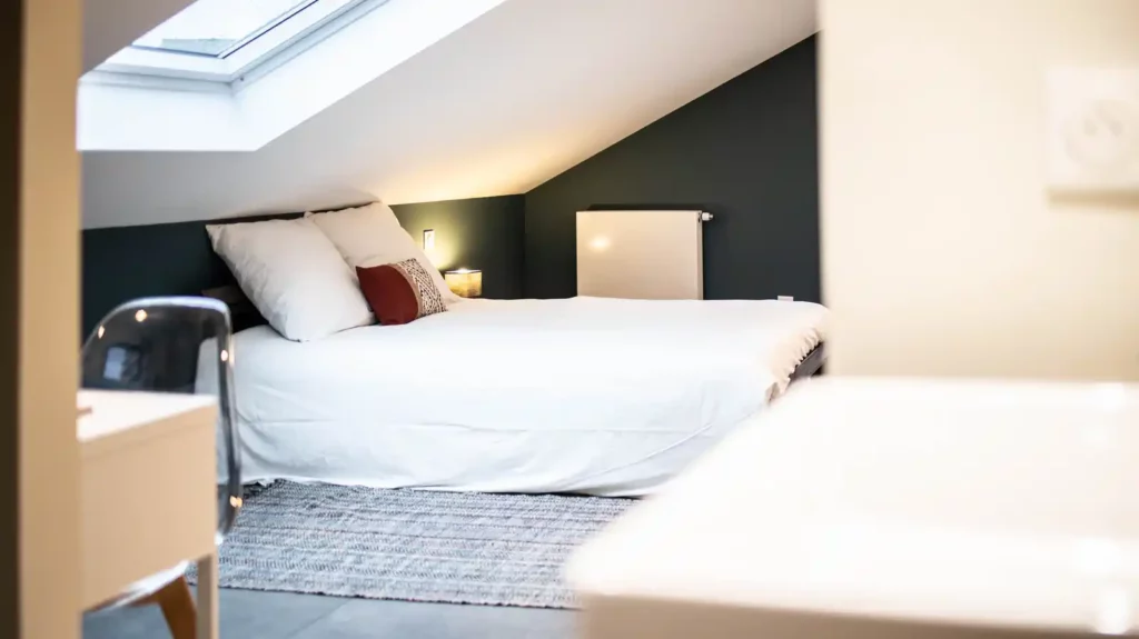 Chambre mansardée avec lit double, fenêtre de toit et mur sombre — Maison Le Quesne, coliving IvyNest à Marcq-en-Barœul