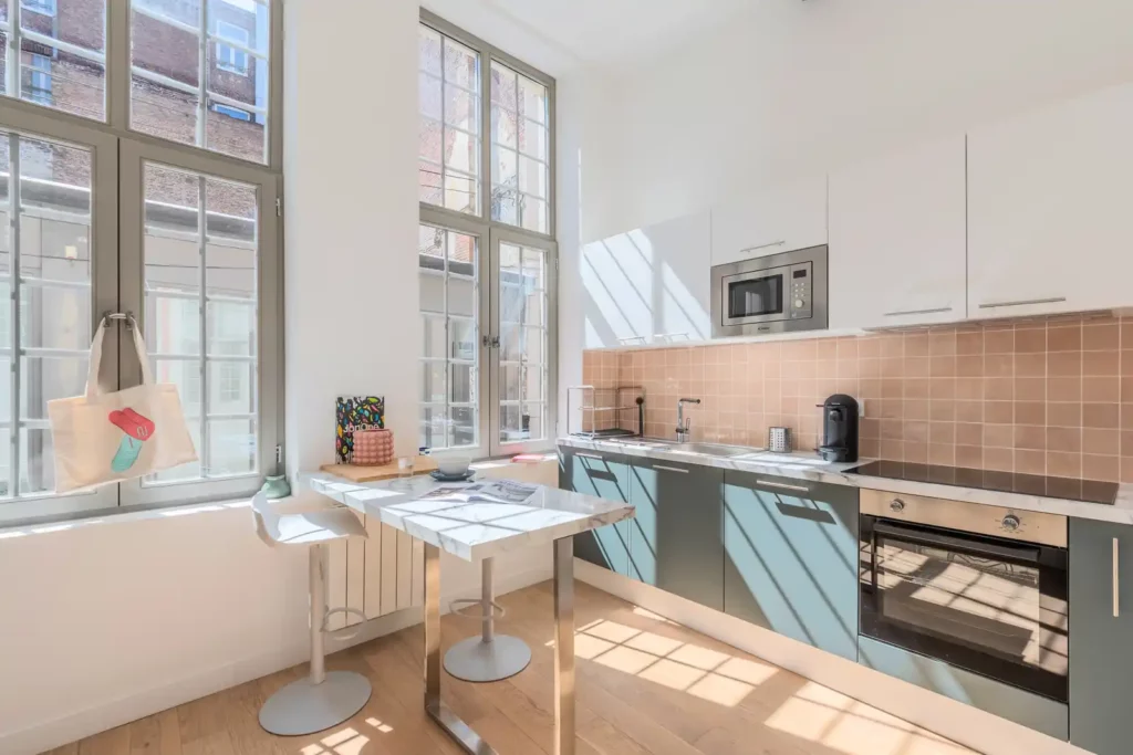 Cuisine équipée avec crédence rose et bar à tabourets — Maison Saint-Étienne, coliving IvyNest à Lille Centre