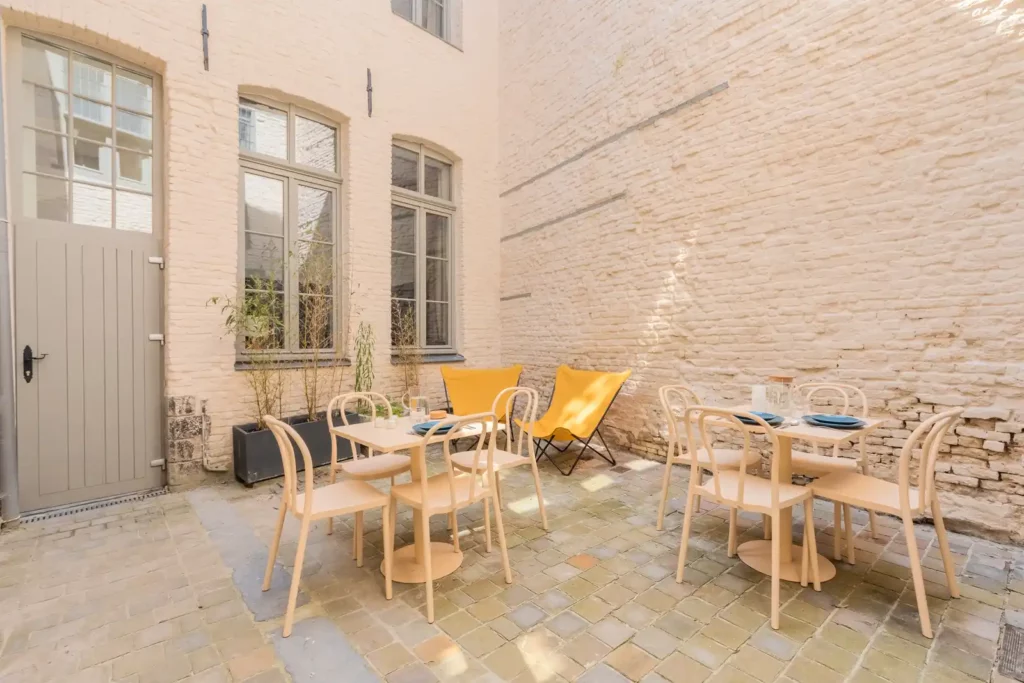 Cour intérieure pavée avec tables, chaises et mur en briques — Maison Saint-Étienne, coliving IvyNest à Lille Centre