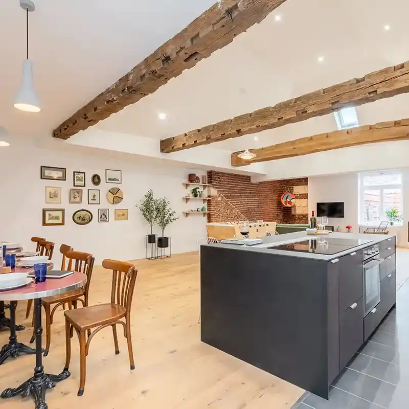 Séjour sous poutres avec îlot noir et table bistrot — Maison Sainte-Catherine, coliving IvyNest à Lille