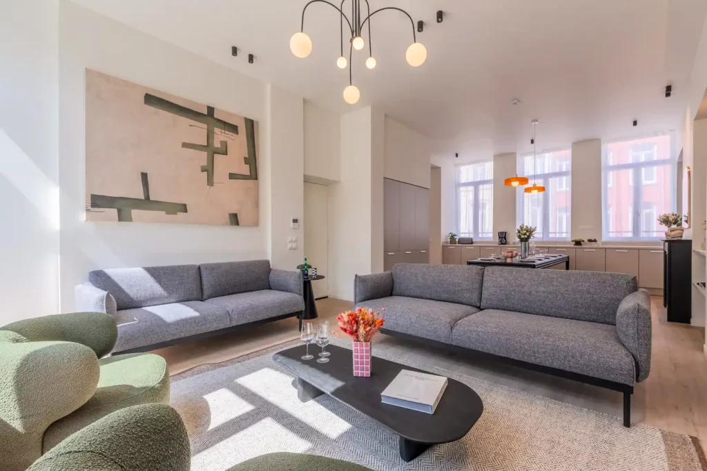 Salon spacieux avec canapés gris et cuisine ouverte au fond — Maison Valmy, coliving IvyNest à Lille République