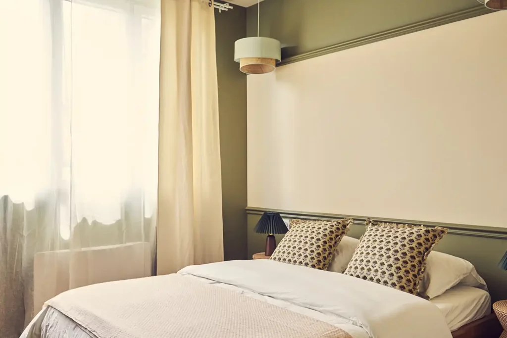 Chambre avec murs vert sauge, lit double et suspension en rotin — Maison Nanterre, coliving IvyNest à Nanterre