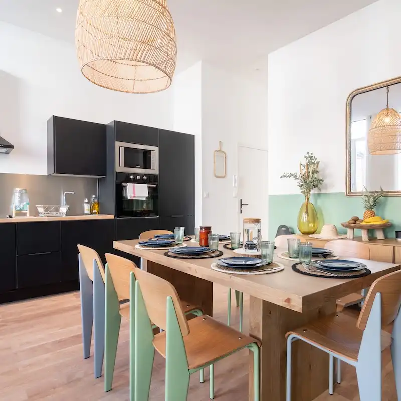 Cuisine noire ouverte sur table en bois et chaises vertes — Maison Colbert, coliving IvyNest à Lille