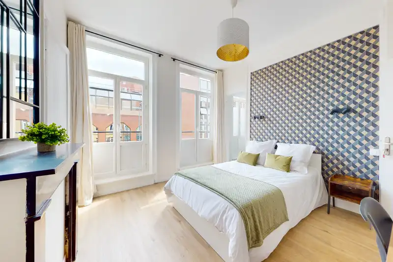 Chambre avec lit double, mur géométrique bleu et jaune, plaid vert olive — Maison Artois, coliving IvyNest à Lille JB Lebas