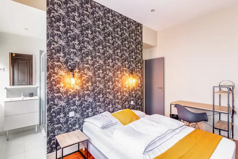 Chambre avec lit double, applique ambrée et bureau — Maison Jeanne d'Arc, coliving IvyNest à Lille République