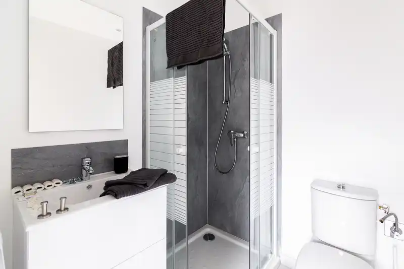 Salle d'eau avec douche vitrée, vasque blanche et toilettes — Maison Jeanne d'Arc, coliving IvyNest à Lille République
