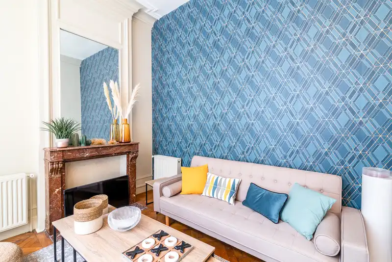 Salon avec canapé rose clair, coussins et mur bleu à motifs — Maison Jeanne d'Arc, coliving IvyNest à Lille République