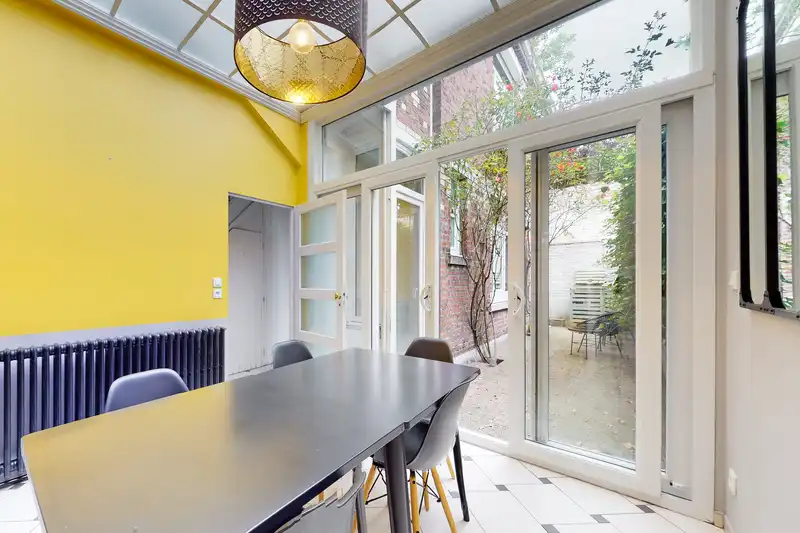 Salle à manger avec longue table noire, mur jaune et portes vitrées — Maison 37 Bigo-Danel, coliving IvyNest à Lille Vauban