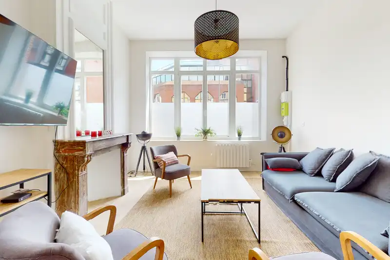 Salon avec canapé gris, fauteuils vintage et télévision murale — Maison Artois, coliving IvyNest à Lille JB Lebas