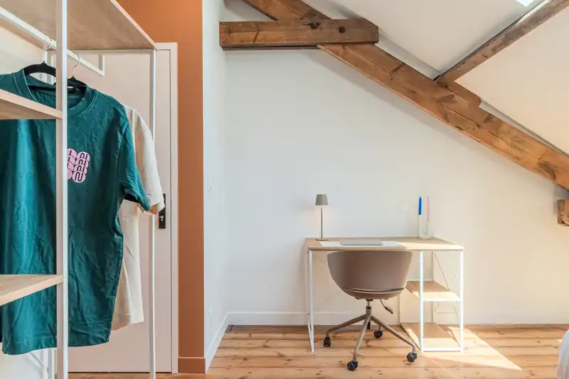 Chambre sous poutres apparentes avec bureau, penderie et mur terracotta — Maison Douai, coliving IvyNest à Lille JB Lebas