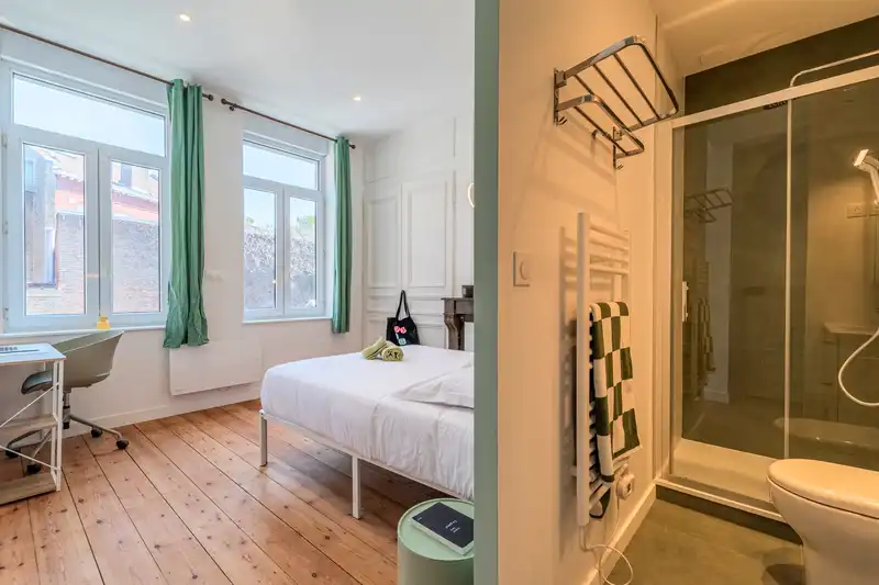 Chambre avec lit, bureau et douche vitrée visible en second plan — Maison Douai, coliving IvyNest à Lille JB Lebas