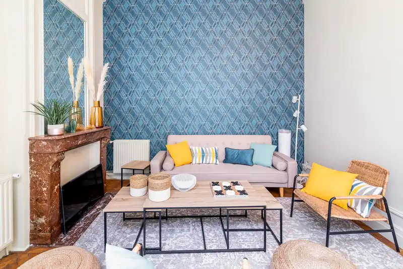 Salon avec mur à motifs bleus, canapé rose et cheminée en marbre — Maison Jeanne d'Arc, coliving IvyNest à Lille République