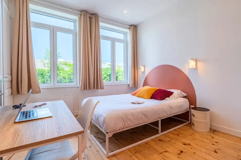 Chambre avec lit double et tête de lit rose arrondie, rideaux beiges — Maison 68 Roland, coliving IvyNest à Lille Vauban