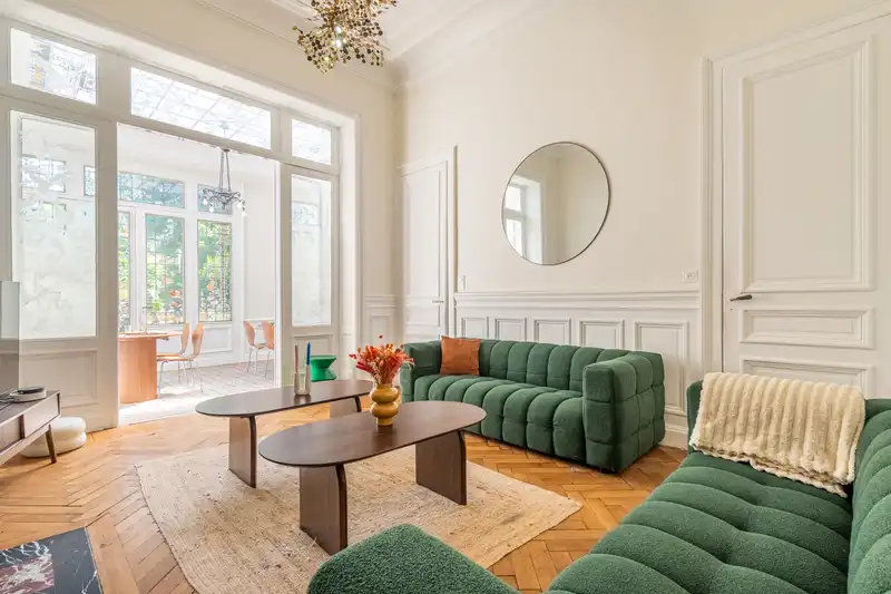 Salon avec canapés verts capitonnés, parquet à chevrons et véranda — Maison 67 Roland, coliving IvyNest à Lille Vauban