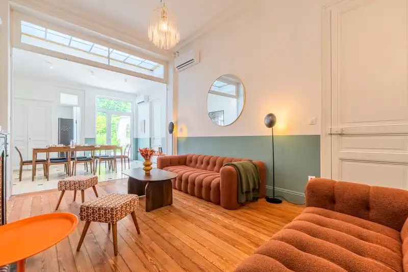 Salon avec canapés orange et mur vert d'eau, salle à manger au fond — Maison 68 Roland, coliving IvyNest à Lille Vauban