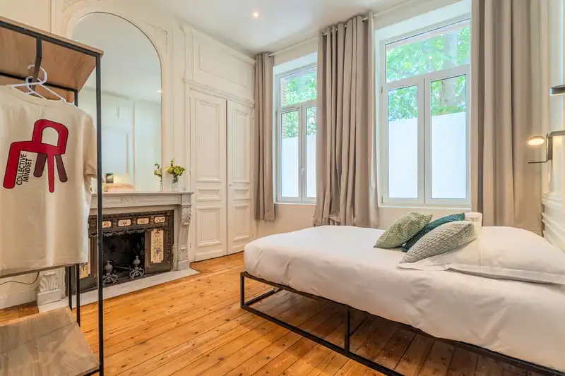 Chambre avec lit bas, cheminée en marbre et grand miroir arqué — Maison Vauban, coliving IvyNest à Lille Vauban