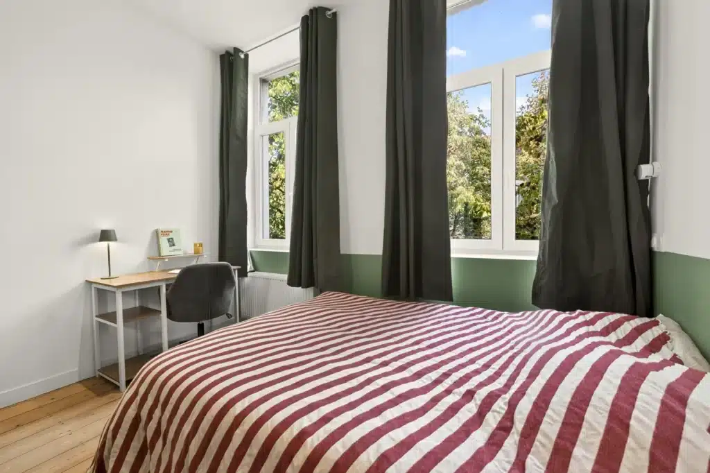 Chambre lumineuse avec mur vert, coliving Lille République